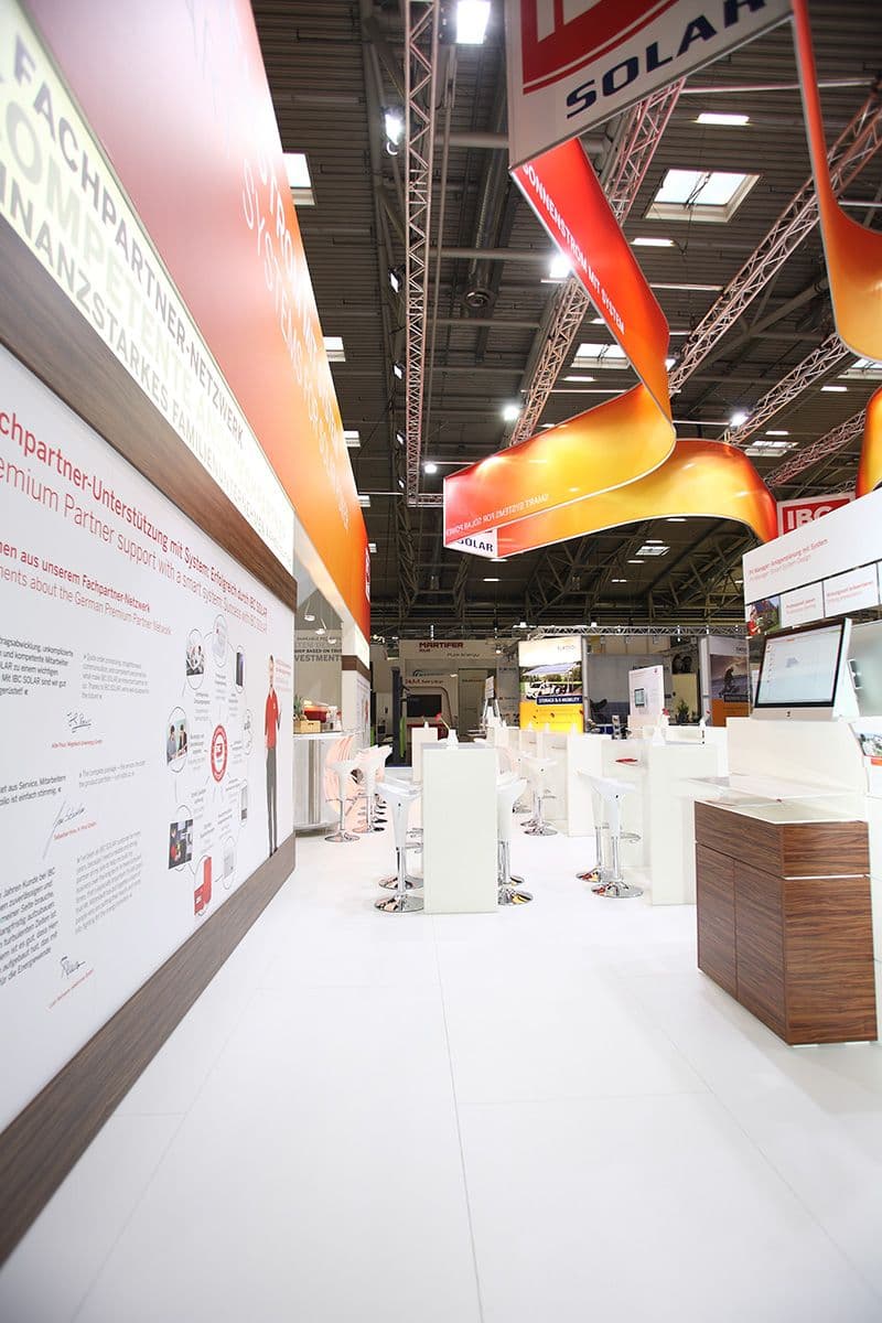 Detailfoto des Messestandes für IBS Solar auf der Intersolar München: Weiße Cuben und rot-gelbe Poster